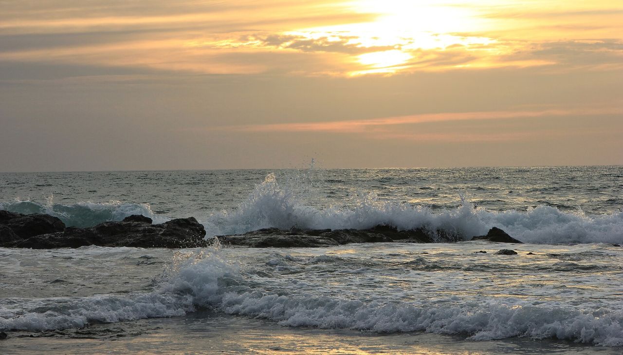 Olas rompiendo sobre las rocas mientras el sol baja sobre el Pacífico